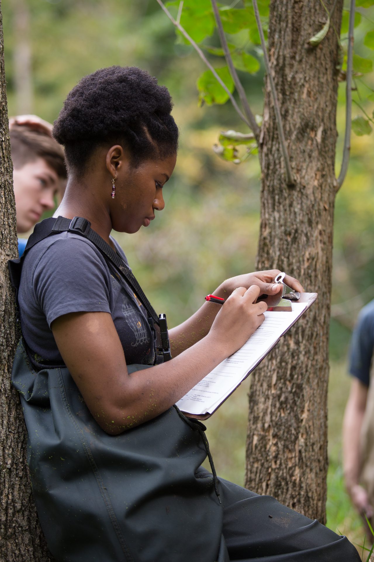 Environmental biology major student in ecology lab outdoors taking notes