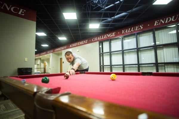 The health and fitness center lobby is a popular spot for students to hang out after a long day, or relax before classes. The lobby has a lounge area with a television that is always playing the latest sports news. Complete with a pool table and ping-pong table, this is also a great spot to get your own competition on. Whether it be challenging the infamous Romanian table tennis champion, Dr. Rata, to a ping-pong match, or organizing a large group game of around-the-world, you’re sure to have a great time! You can also access our campus store from the lobby where you will find a wide selection of Lancer apparel. But you don’t have to wait until the campus opens to shop! Shop now. Stop #2: The Fitness Room  You can’t miss our 4,000 square-foot fitness center equipped with a 17-piece line of Cybex Eagle strength equipment, and a full range of free-weight equipment. Grab your workout buddy, and start racking up! The room also boasts in its cardio center which provides 12 High-Tech Life Fitness cardio machines including six treadmills, three ellipticals, and three stationary bikes. The latest additions include two Stair Masters and a rowing machine as well. Stop #3: The Aerobics Room  Did you know that Grace provides free group fitness classes during the school year at its health and fitness center? These classes take place at a variety of times to fit your schedule and meet a variety of fitness levels and needs. Some of our classes include Athletic Yoga, p90X, Strong, and Piyo. Oh...and we cannot forget the ever-popular Zumba classes in the evening! Find a complete list on our GHAWC Facebook page! All of this, and more, takes place in our 2,800 square-foot aerobics room complete with a wood floor and wall-mounted ballet bars. Stop #4: The Fieldhouse Our fieldhouse is a 32,000 square-foot enclosed room which includes four basketball courts, an 80-yard six-lane straight track, a 1/10 mile four-lane indoor oval track, volleyball nets and two batting cages. This room serves many purposes for the Grace College and Warsaw community. It transforms into a boat-part store and boat-assembly station for our annual freshman event The Hike.  The GHAWC houses our annual Lancer camps where kids from the community develop their athletic skills under the coaching of our Lancer athletes.  It is the setting for our intramural basketball and volleyball games that take place at 9 p.m. - 11:50 p.m. on weeknights. (Did we mention college shakes things up for the sleepy-heads?) And it is also where many events for our campus-wide competition, The Joust, take place -- whether it be a 90-player game of knock out, an obstacle race, or a spikeball show-down. The GHAWC also transforms into a children’s marketplace where community kids’ clothing and toys are sold to raise money for Kid’s Market Inc.  Stop #5: The Athletic Performance Room Tucked behind our frequented fitness room is a space that our varsity athletic teams utilize on a regular basis for team training and meetings. This 1,300 square-foot Athletic Performance room contains Hammer Strength combo racks, a full set of DB free weights, Vertimax trainer, and plenty of agility equipment located on a turf flooring. Stop #6: The Golf Room Some might not know about the state-of-the-art indoor putting green we have! This is the perfect space for our golf players to “tee-it-up” on a cold or rainy day when the course is closed! So now that we’ve “taken you around” the health and fitness center, you should know that the GHAWC is not just for Grace students. The way of Grace leads us to be generous with what we’ve been given, so we’ve extended the invitation to several additional groups in our community: Grace College & Seminary employees and their spouses Grace College & Seminary alumni and their spouses Community senior citizens – age 60 and up (must obtain medical release) Local law enforcement and fire/ems personnel If you fall into one of these categories, (hopefully!) we will see you at the health and fitness center soon!