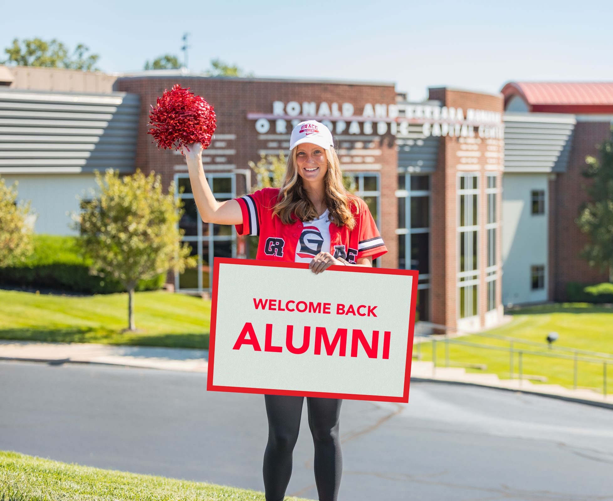 Grace College student with welcome sign for Grace College Alumni